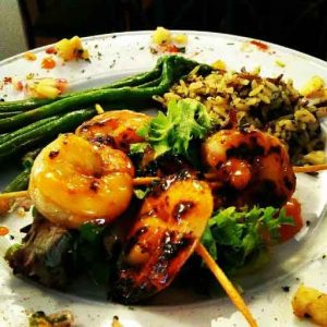 Shrimp on skewers with green beans and rice.