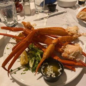 A plate of crab legs and a glass of wine on a table.